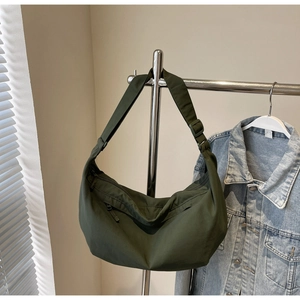 Detail of a dark green nylon crescent bag with adjustable strap and front zipper pocket