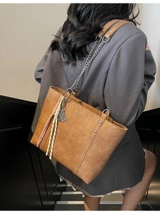 Brown large capacity leather tote bag with rivets, chain strap and woven pendant