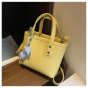 Detail of yellow lychee grain leather mini bucket bag with a blue floral charm