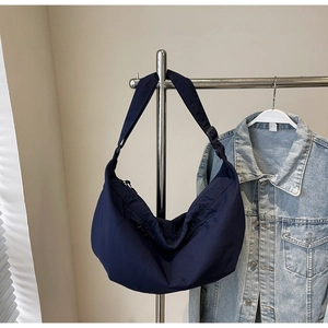 Detailed view of dark blue nylon crescent bag with adjustable strap and zip closure