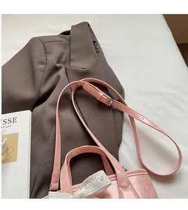 Dettaglio di una borsa a secchiello rosa lucido con fiocco in pizzo bianco e tracolla