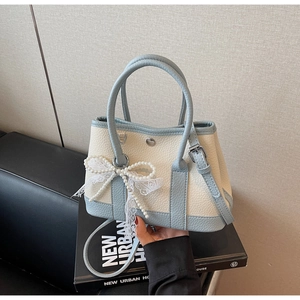 Detail of blue and white bucket bag featuring pearl bow and delicate lace accents