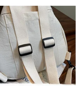 Dettaglio di spalline in tessuto regolabili e fibbie nere su uno zaino in nylon