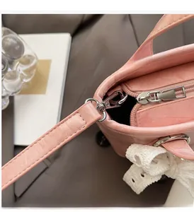 Dettaglio borsa a secchiello rosa con finiture argento e fiocco di pizzo bianco