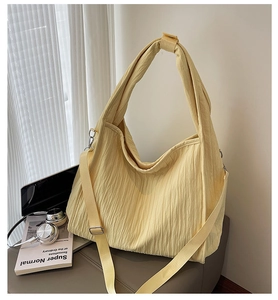 Detail of light yellow pleated canvas tote with adjustable strap and vertical texture