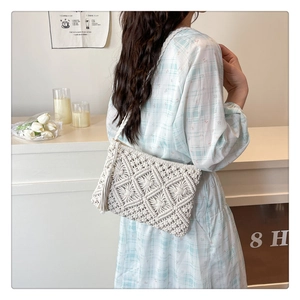 Close-up of white handmade knit crochet shoulder bag featuring retro hollow lattice and tassel