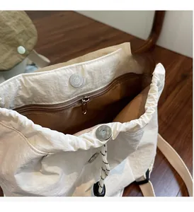 Dettaglio interno della borsa a secchiello beige con chiusura magnetica e tasca zip