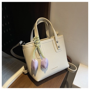 Detail of lychee pattern leather mini bucket bag with purple tulip charm and shoulder strap