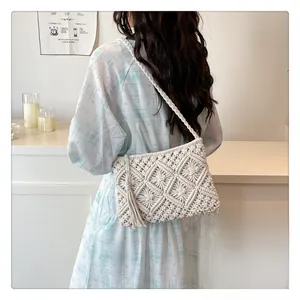 Detail of white hollowed-out crochet bag with long side tassels and bohemian woven pattern
