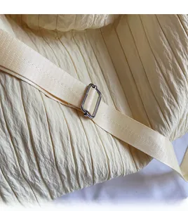 Close-up of cream textured tote with adjustable nylon strap and silver metal buckle