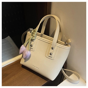 Detailed shot of cream lychee leather bucket bag with purple flower charm and silver hardware
