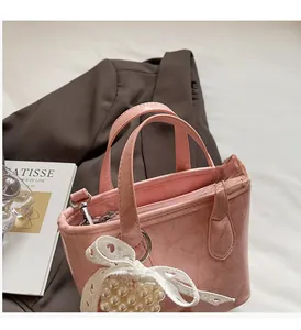 Dettaglio della borsa a secchiello rosa in pelle PU con ciondolo di perle e pizzo