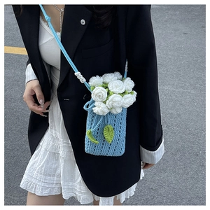 Dettaglio della borsa a secchiello blu chiaro all'uncinetto con fiori 3D sul modello
