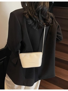 Cream white woven texture crossbody bag shown from a back perspective on model