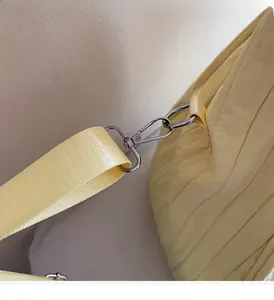 Detail of silver metal hook and pleated fabric texture on light yellow tote bag