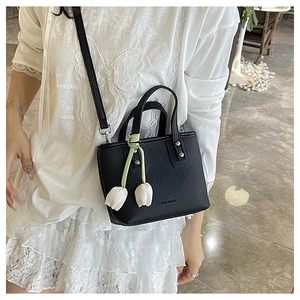 Close-up of black lychee texture bucket bag with metal rivets and tulip charm detail