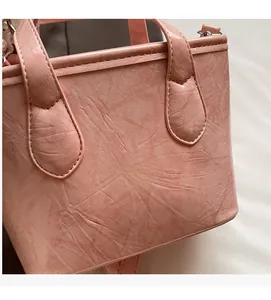 Dettaglio della borsa a secchiello rosa con trama in pelle pieghettata e cuciture