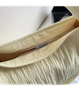 Detail of silver smooth metal zipper and vertical pleated texture on yellow nylon tote