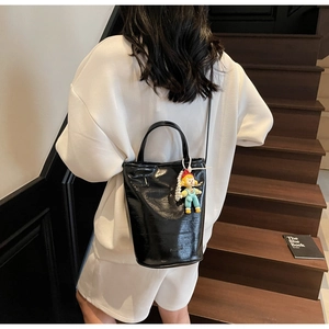 Détail du sac seau en cuir verni noir brillant avec logo FASHION et pendentif rigolo
