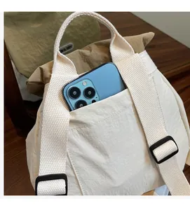 Dettaglio della resistente tasca esterna della borsa tote in nylon con uno smartphone blu