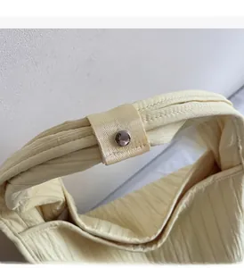 Detail of the cream fabric tote bag showing the sturdy handle and silver metal snap button