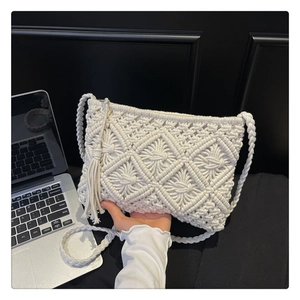 Macro view of beige crochet bag featuring geometric patterns and side tassel accents