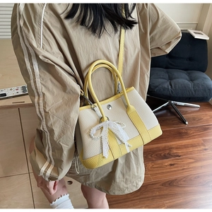Chic cream and yellow bucket bag featuring a decorative pearl lace bow and dual straps