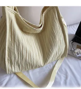 Close-up of beige tote bag showing unique pleated fabric texture and soft fabric strap