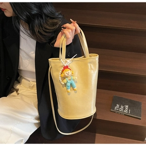 Detail van crème bucket bag met krokodillenstructuur en schattige pop op houten trap
