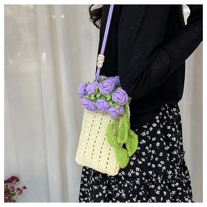 Dettaglio della borsa a secchiello lavorata a mano con fiori viola e tracolla sottile