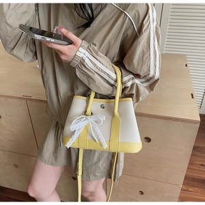 Detail of crossbody bucket bag featuring lace pearl bow charm and lychee texture