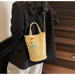 Détail du sac seau beige minimaliste avec breloque et bandoulière ajustable