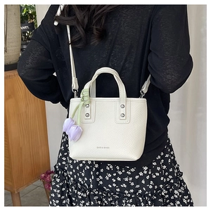 Rear view of cream litchi grain bucket bag with tulip charm worn as a crossbody