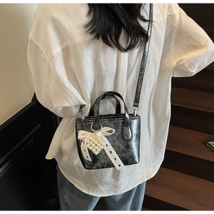 Dettaglio della borsa vintage nera con cuore di perle e decorazione con fiocco in pizzo