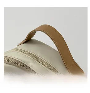 Detail of beige nylon backpack featuring brown faux leather handle and sturdy zippers