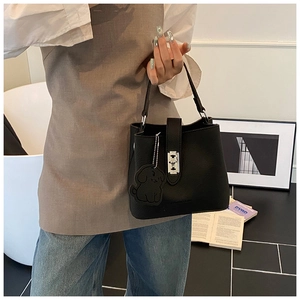 Dettaglio di una borsa a secchiello nera con chiusura a scatto e ciondolo a cane