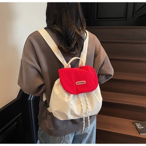 Detail of red and white bucket backpack featuring a drawstring closure and brand label