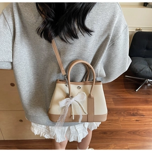 Detail of mini bucket bag with lace bow, pearl pendant and leather crossbody strap