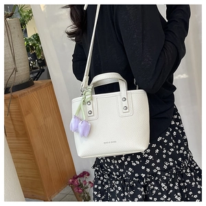 Close-up of white pebble leather bucket bag with DADI & BAGS logo and tulip charm