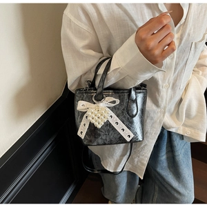 Dettaglio mini borsa tote grigio scuro con fiocco in pizzo bianco e ciondolo a cuore
