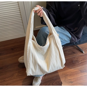 Detailed view of large cream tote bag with vertical stripes and wide shoulder strap