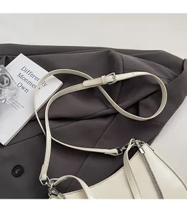 Detail of adjustable strap and silver chain on an off-white minimalist shoulder bag