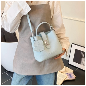 Dettaglio borsa a secchiello azzurra con trama litchi, chiusura in metallo e charm