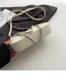 Detail view of reinforced flat base and smooth leather texture of beige shoulder bag