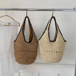 Detail of hand-woven hollow patterns on beige straw tote bags with black crochet trim