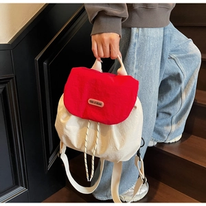 Detail of red and cream backpack with drawstring closure and metal brand logo plate