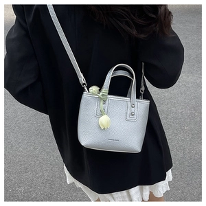 Silver lychee grain leather mini bucket bag shown as a crossbody on a street style model