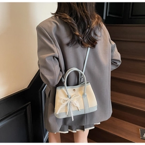 Micro bucket bag with beige lychee texture, light blue leather trim and pearl lace bow