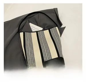 Detailed view of striped canvas tote with black leather bottom and shoulder strap