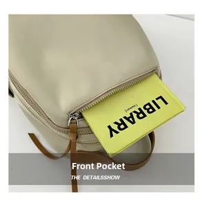 Detailed view of the front zipper pocket on a beige travel backpack showing book storage